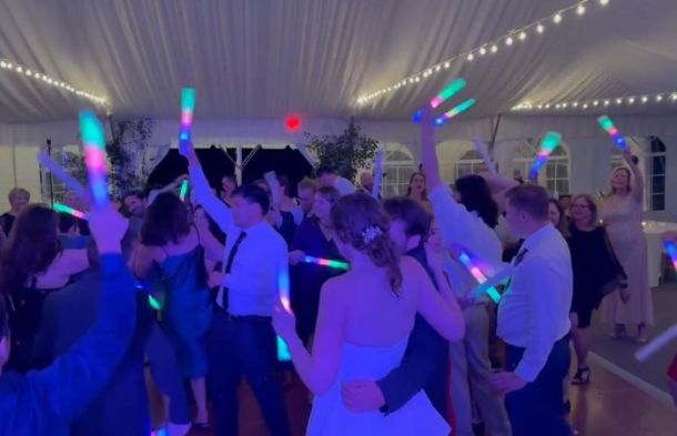 A group of people dancing at a wedding waving our light sticks.